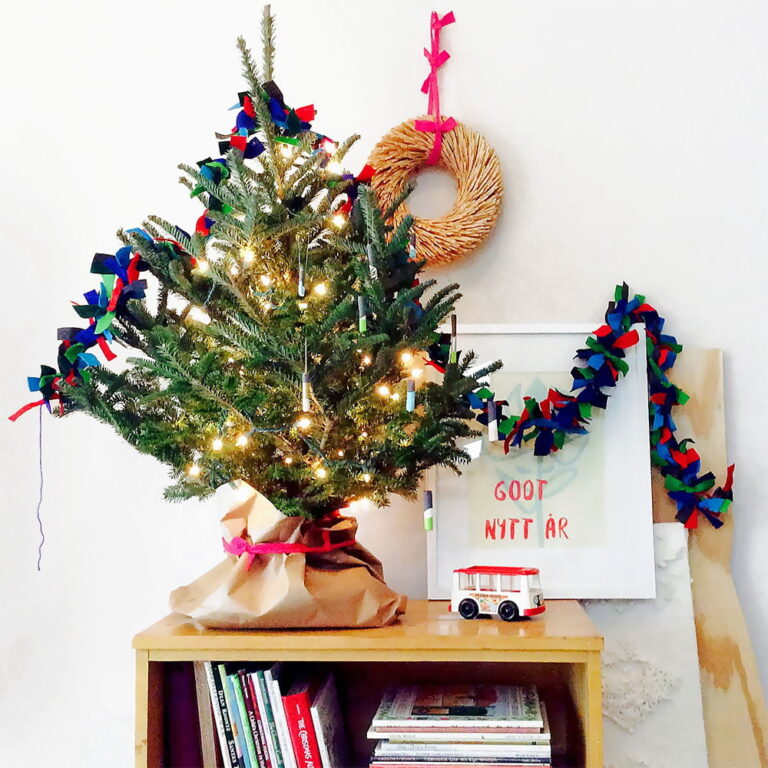 Our DIY felt garland hanging over a small tree on a tabletop in front of a white background.