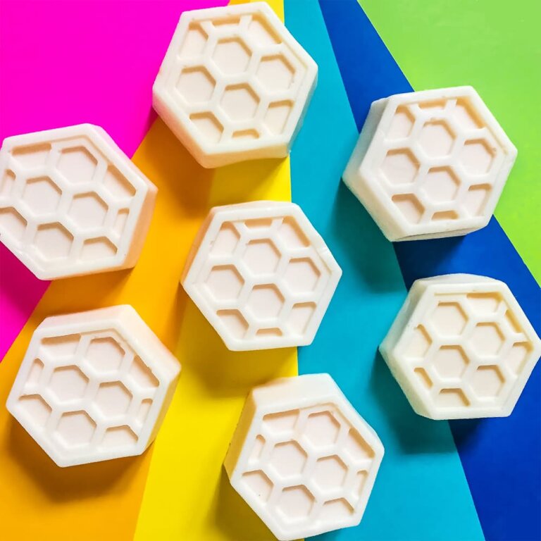 Our DIY honey goats milk soap bars sitting on a colorful rainbow background