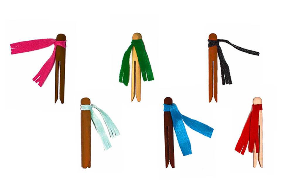 Six diverse winter clothespin dolls sitting on a white background