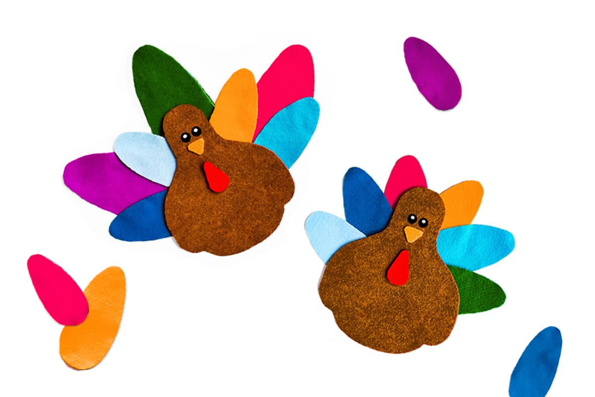 Our felt turkeys sitting on a white background with colorful felt turkey feathers