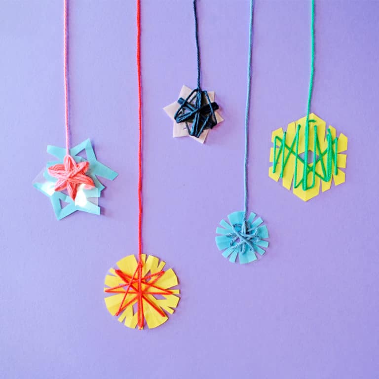 Five colorful yarn-wrapped snowflakes sitting on a purple background