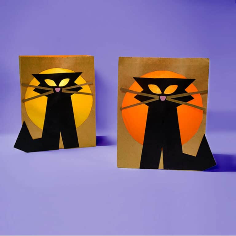 A pair of our black cat paper bag luminaries lit with flameless tea lights