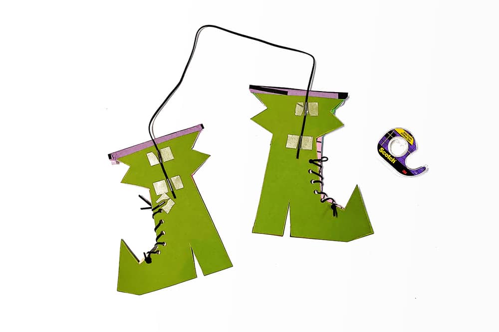 Tape a ribbon or string to the back of both of your witch's boots to hang them.