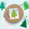 Printed evergreen lacing card pages from our Pine Tree Art Template Bundle for kids sitting on a blue background.