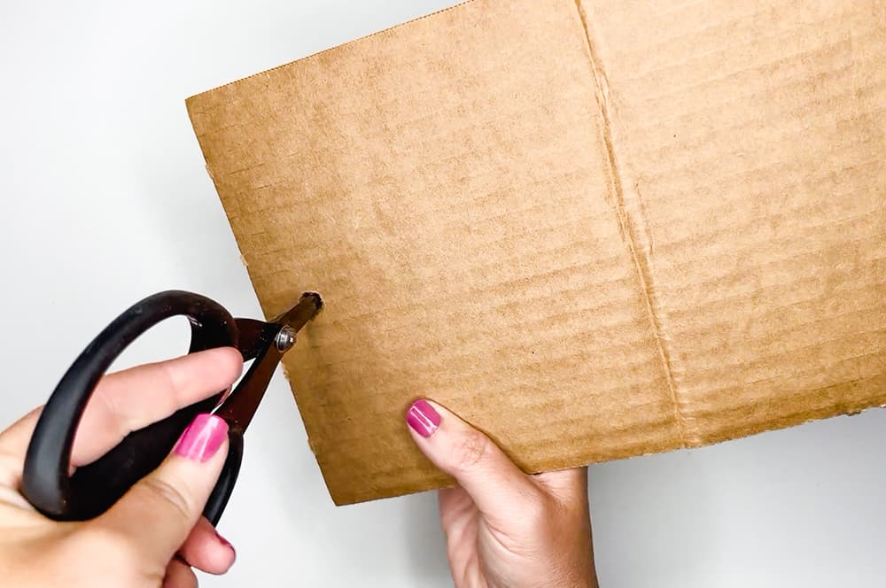 Cutting a hole in cardboard to make a cardboard bird feeder