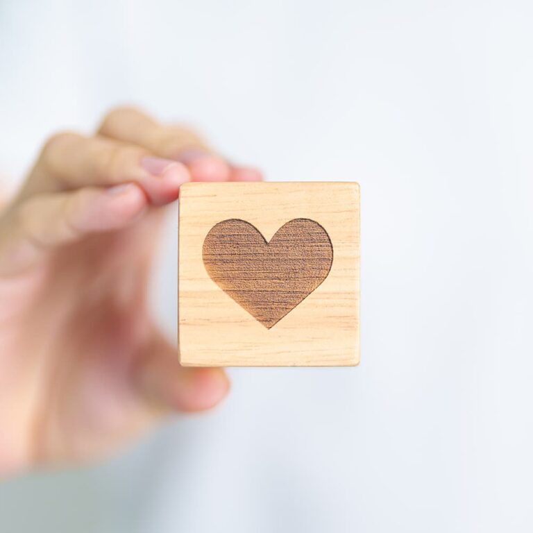 A child holding a wooden block with a heart on the side