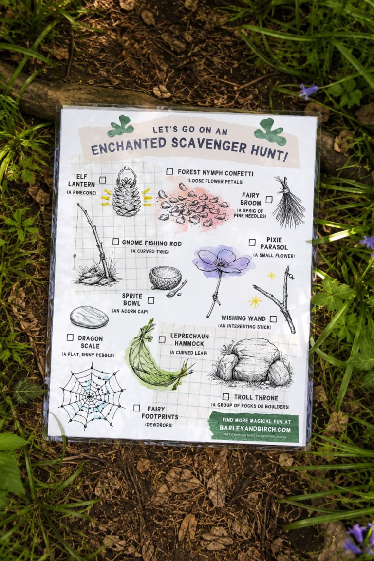 An illustrated printable fairy scavenger hunt paper sheet sitting in a mulched path surrounded on either side by green spring foliage